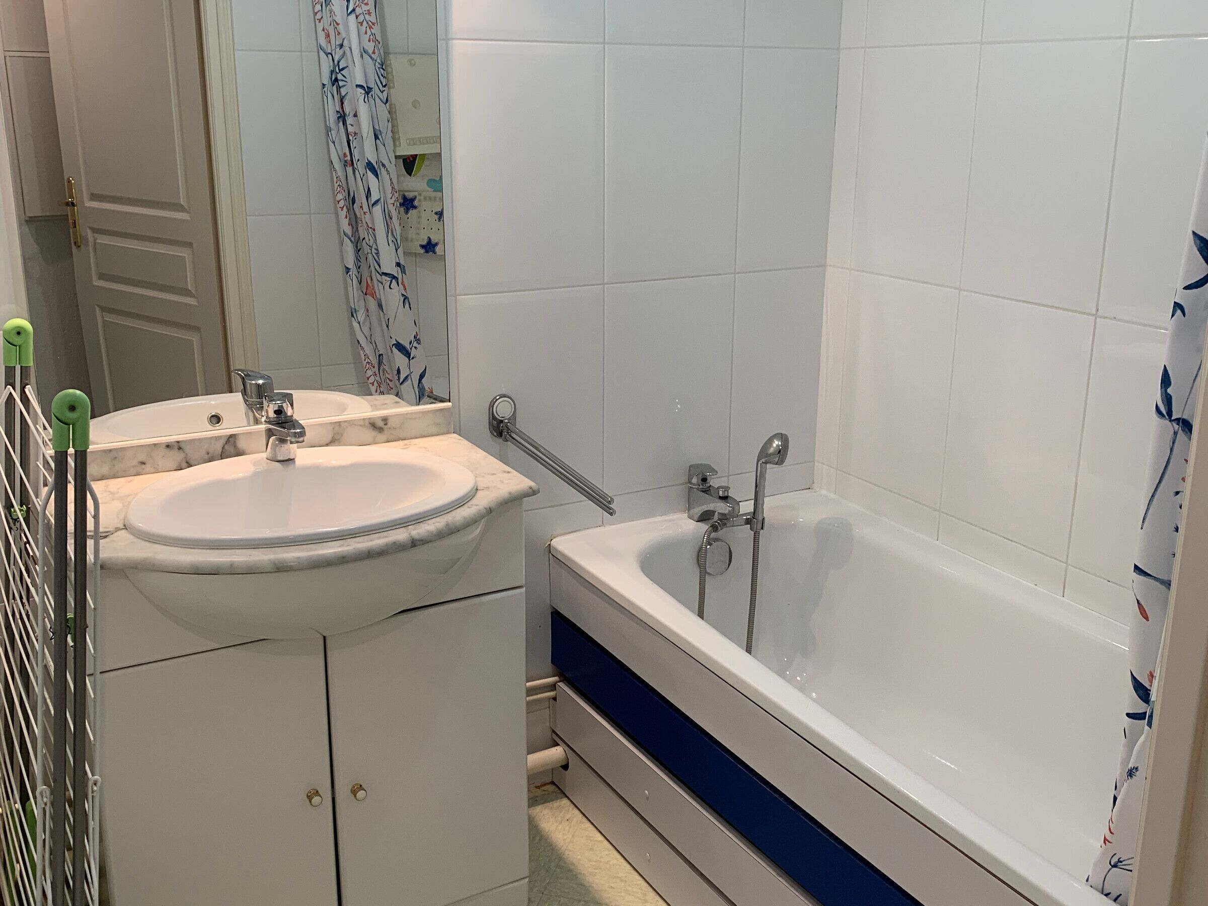 Une salle de bain avec un lavabo blanc, une baignoire et un miroir.