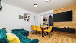 Una sala de estar moderna con un sofá azul turquesa, cojines amarillos y un comedor con sillas amarillas.
