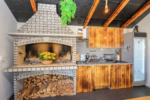 A kitchen with a built-in wood-burning stove, a coffee maker, and a refrigerator. - House Scaena (Crikvenica)