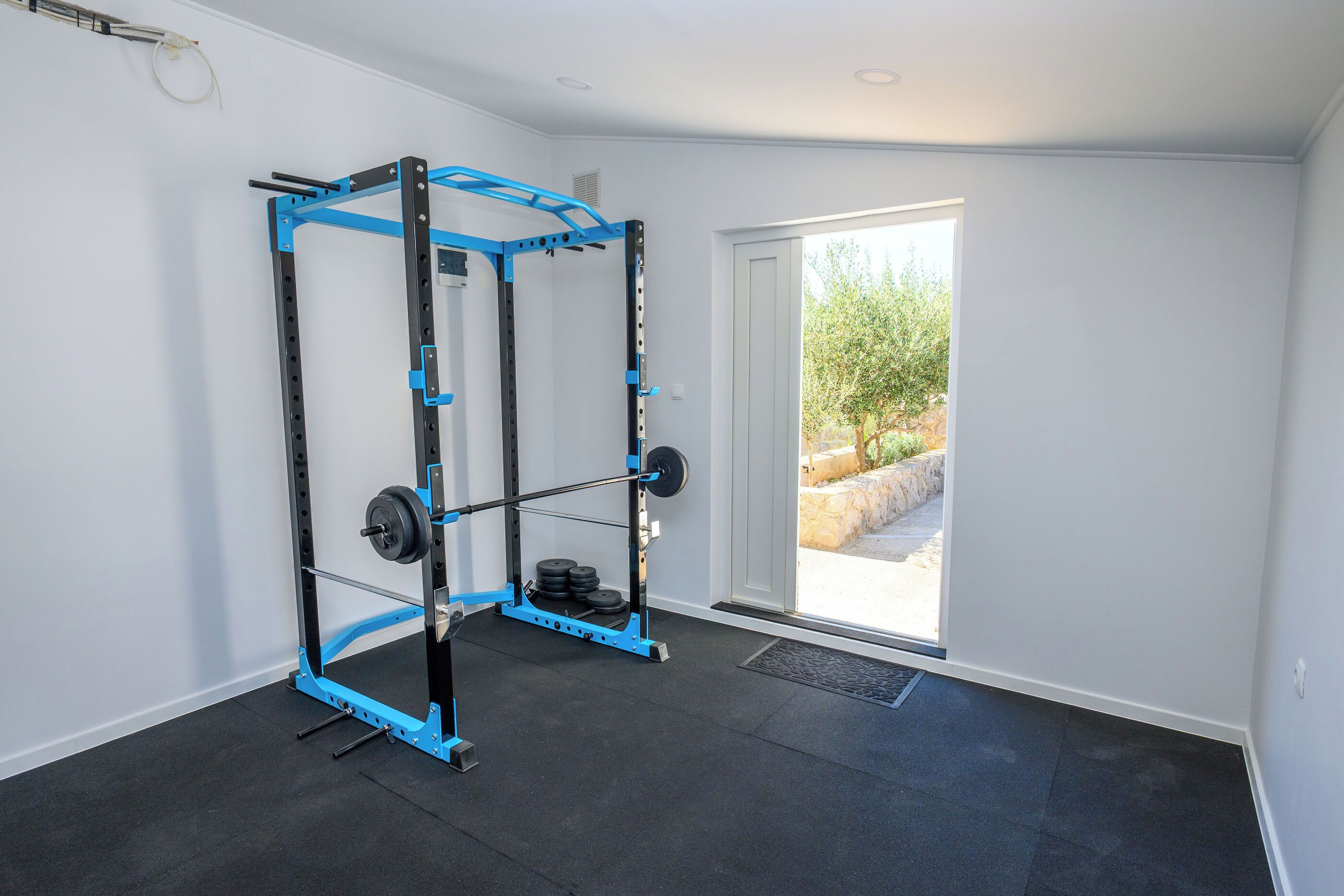 A gym with a squat rack, barbell, and weight plates.
