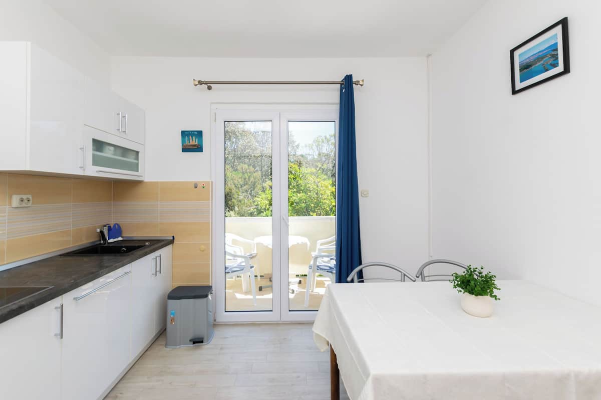 A compact kitchen with a sink, cabinets, and a view to an outdoor seating area.