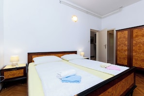 Ein Hotelzimmer mit zwei Betten, Holz-Kopfteilen, Nachttischen inklusive Lampen und einem Kleiderschrank.
