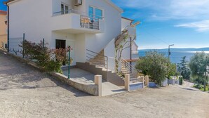 Ein zweistöckiges Haus mit Balkon, Treppe und Meerblick.