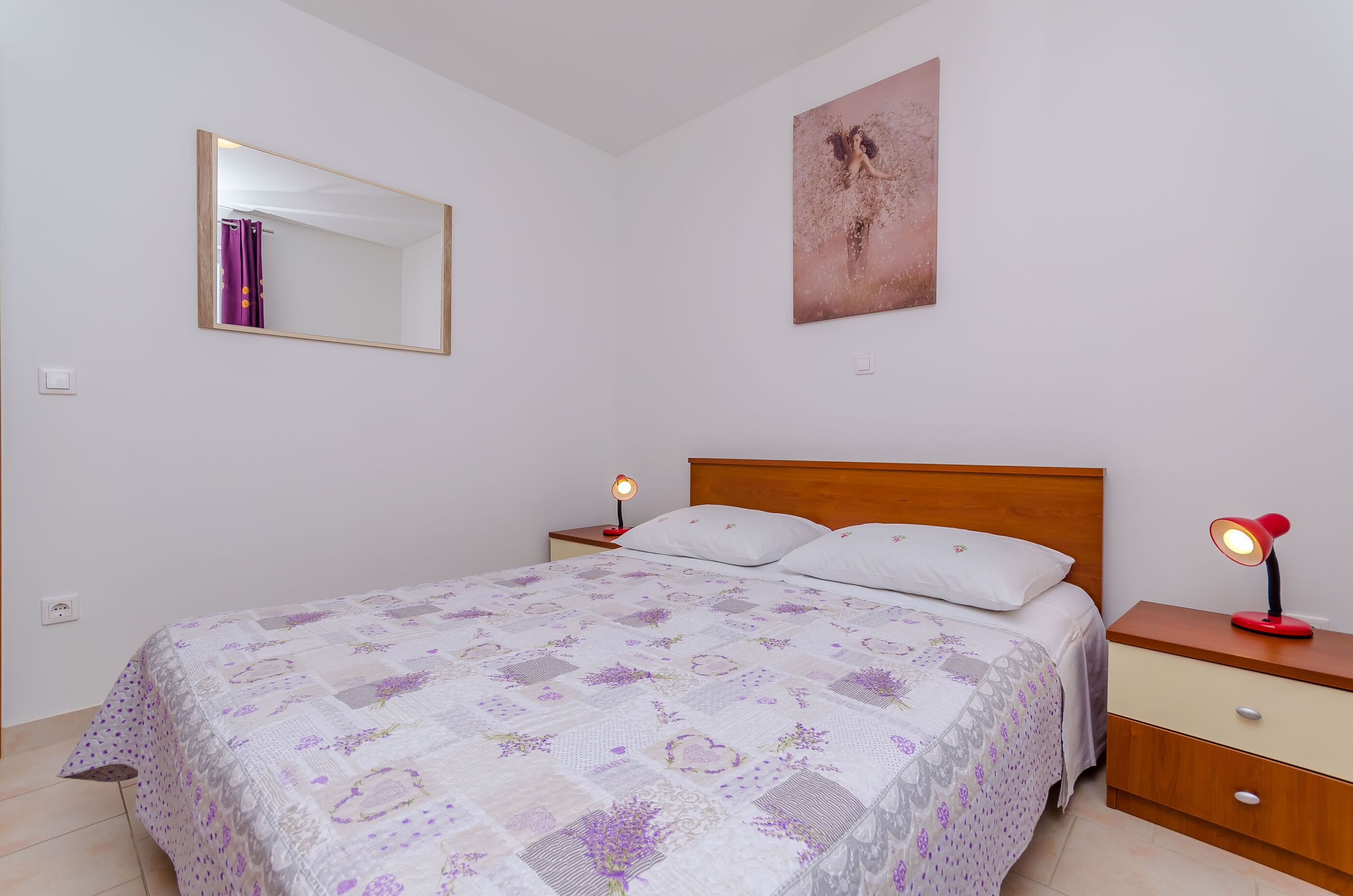 Una camera da letto con un letto, due comodini, uno specchio e un'opera d'arte appesa al muro.
