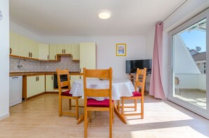Una cocina funcional con armarios de madera y una zona de comedor con mesa y sillas.