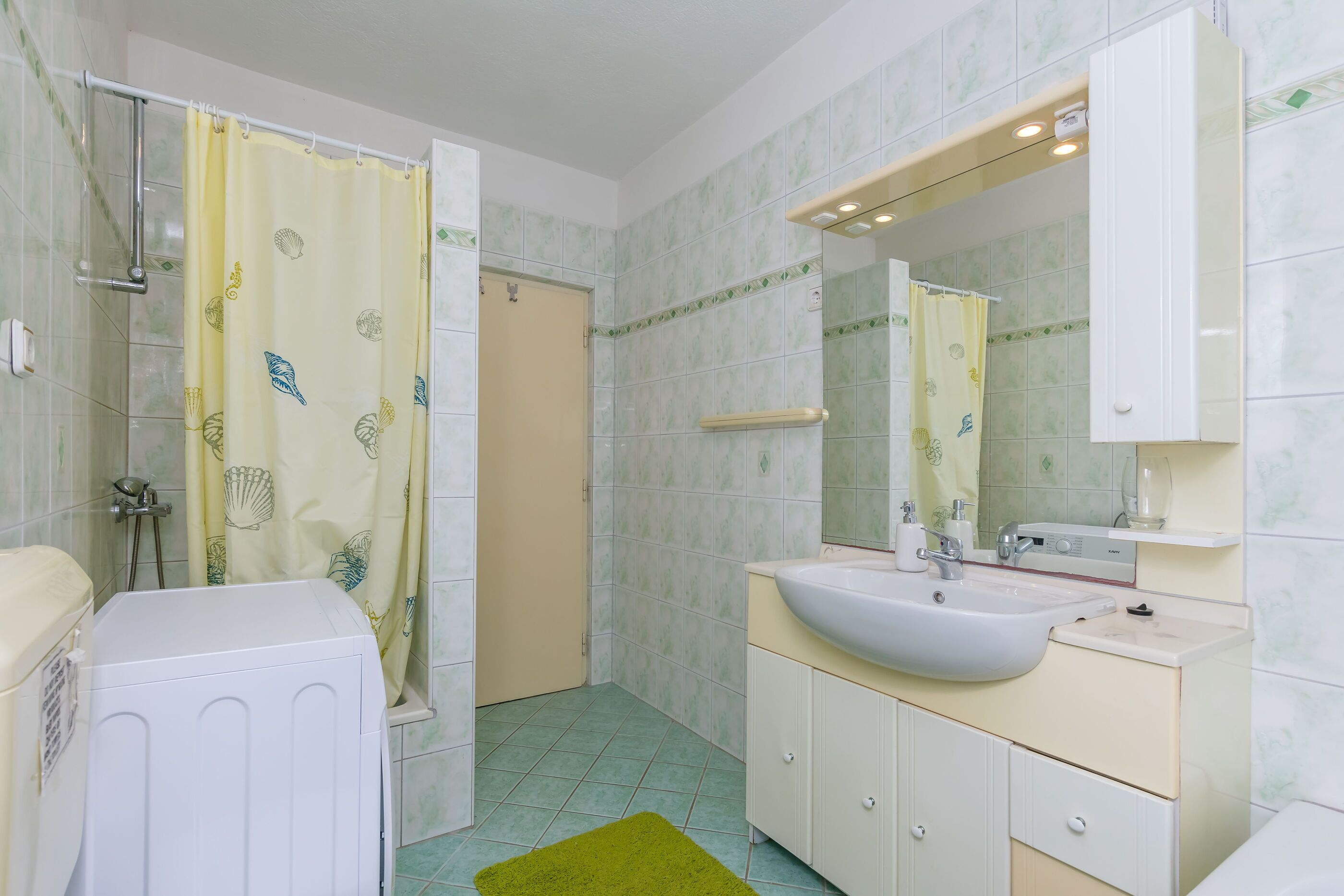 Un baño con ducha, inodoro, lavabo y espejo.