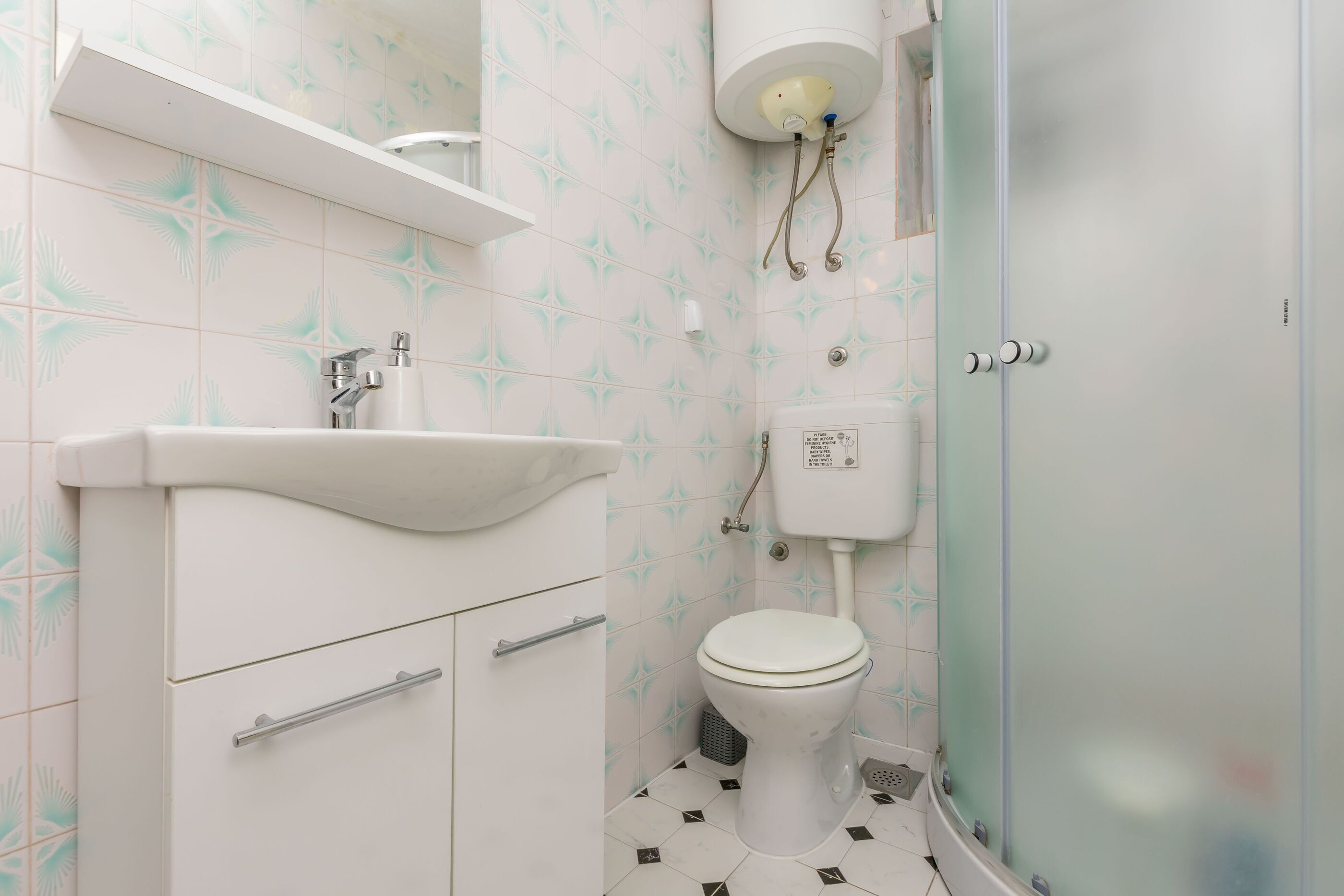 Ein Badezimmer mit weißem Waschbecken, WC und Duschkabine.
