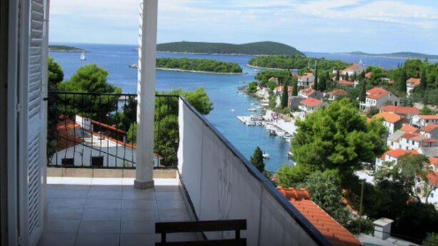 A balcony with a view of a coastal town, a clear sky, and a body of water. - Apartments Vesna (Solta)