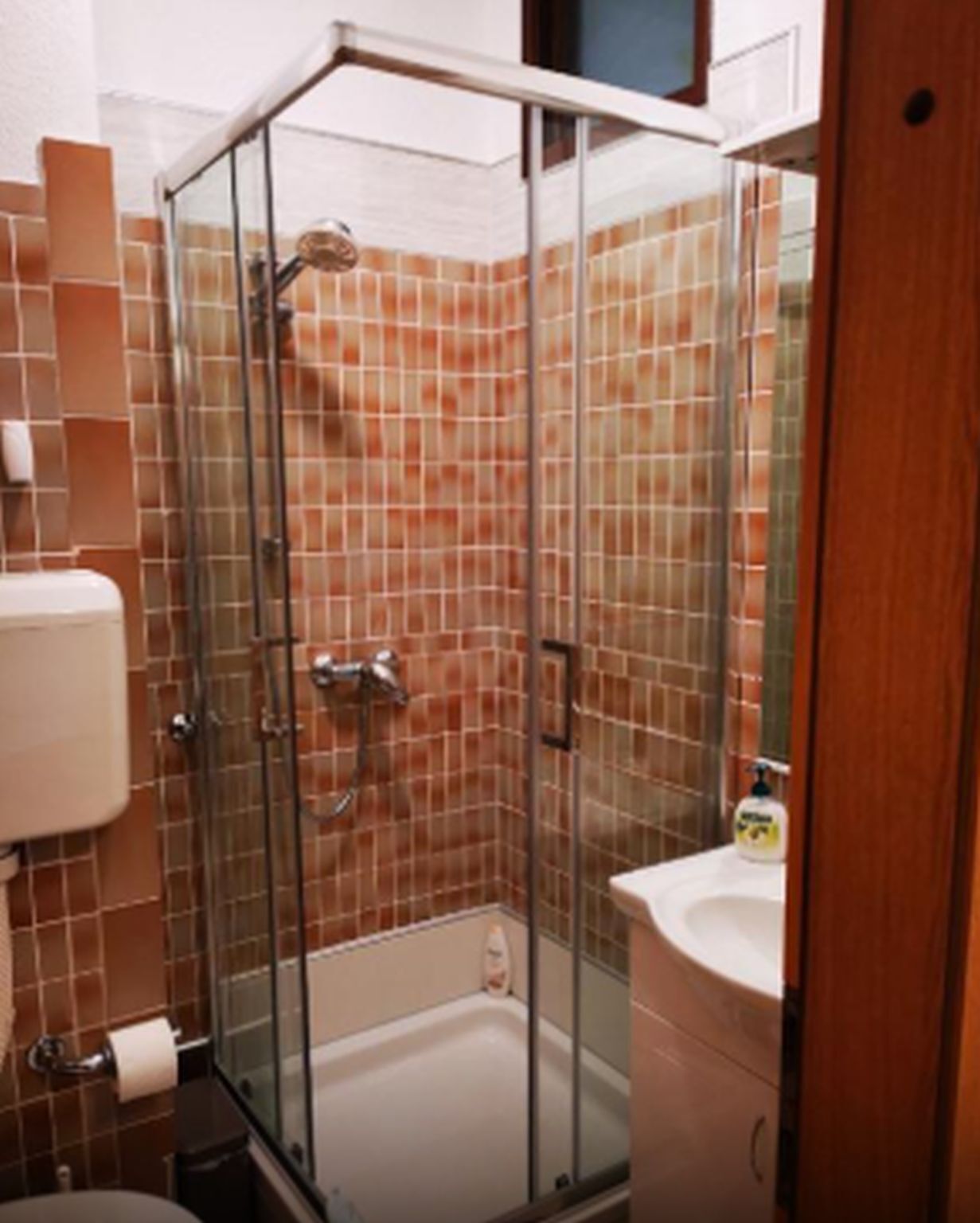A bathroom with a glass shower enclosure, a toilet, and a sink.