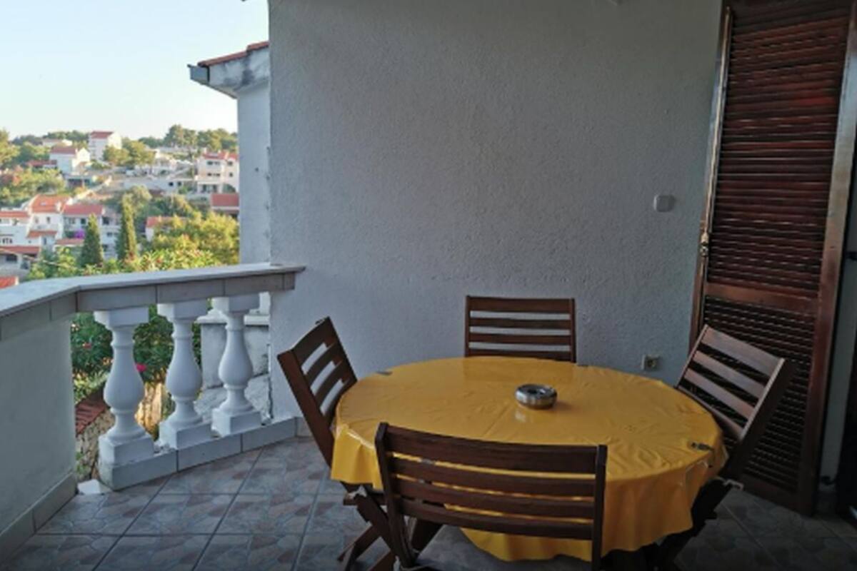 Un balcon avec une table ronde et des chaises, une vue sur la ville et une porte fermée.