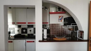 A compact kitchen with white cabinets, a microwave, and a coffee maker. - Apartments Vesna (Solta)