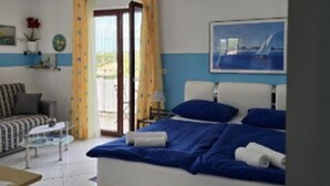 A bedroom with a bed, a ceiling fan, a window with curtains, a painting on the wall, and a view of the outdoors. - Apartments Vesna (Solta)