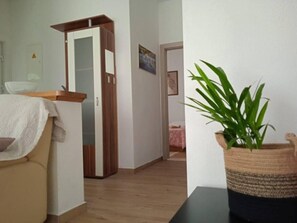 Une pièce avec une porte en bois, une plante en pot et un canapé beige.
