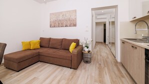 A modern living room with a brown sectional sofa, a small side table with a plant, and a painting on the wall. - Apartments Margita 2 (Vinodol)