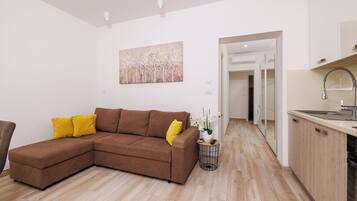 A modern living room with a brown sectional sofa, a small side table with a plant, and a painting on the wall.