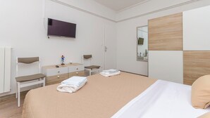 Ein modernes Hotelzimmer mit einem großen Bett, einem flachbildfernseher an der Wand, einer Wand mit Holzpaneelen und einem kleinen Schreibtisch mit Stuhl.