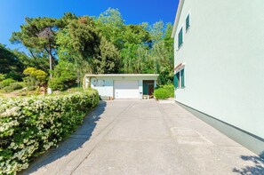 A residential property with a garage, a driveway, and a hedge. - Apartments Ruzica M (Lopar)