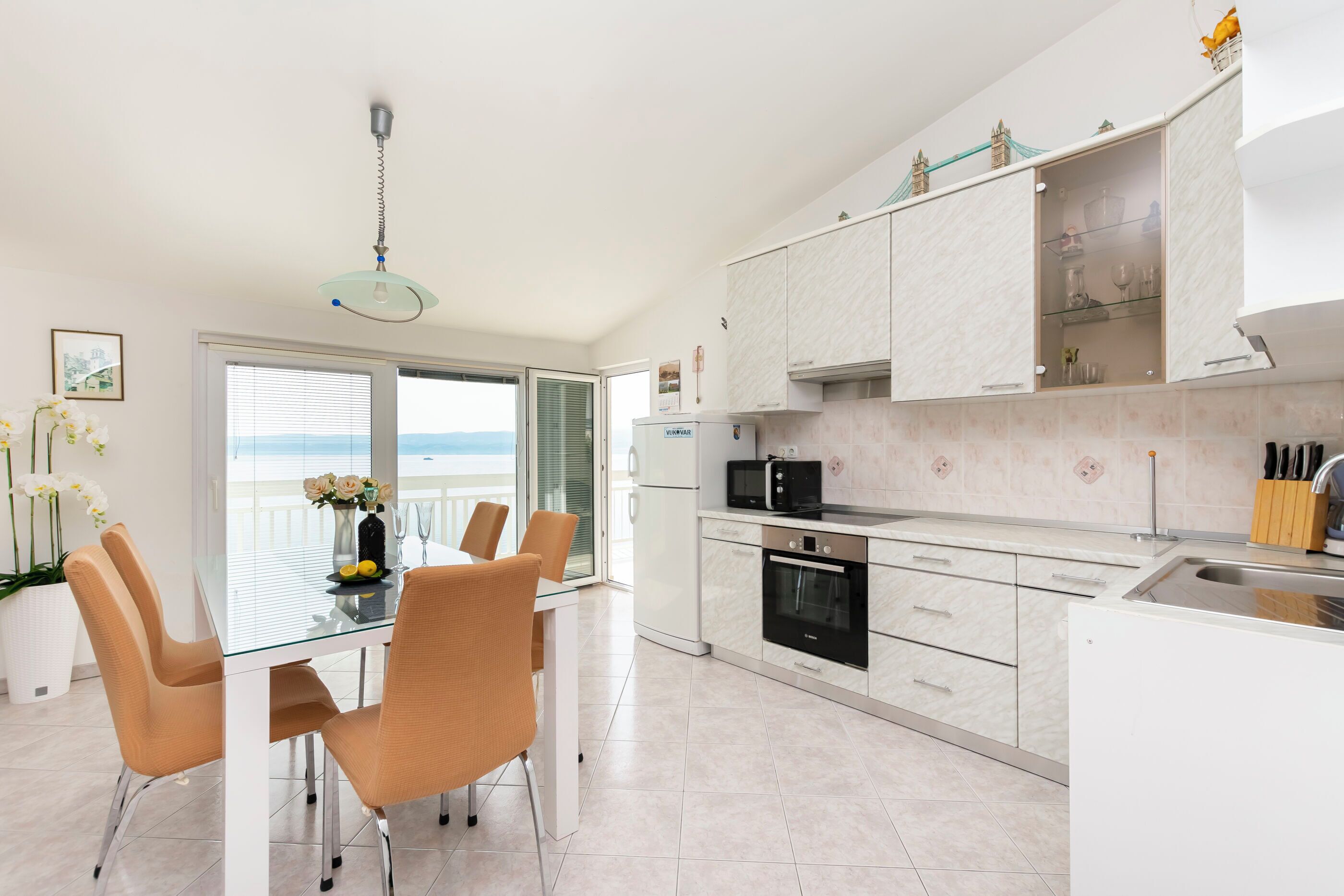 A modern kitchen with white cabinetry, a built-in oven, and a microwave.