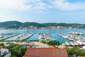 A marina with numerous boats docked, surrounded by hills and a small town in the background. - Apartments Sabina (Rab)