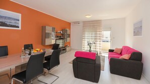 A modern living room with a dining area, featuring a sofa, a coffee table, and a TV. - Apartment Fourstars (Vodice)