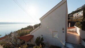 Un edificio blanco con techo inclinado, una ventana pequeña y un balcón.