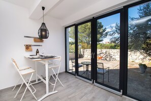 Ein moderner Essbereich mit Tisch und Stühlen, einer hängenden Leuchte und Blick auf die Terrasse durch große Schiebeglastüren.