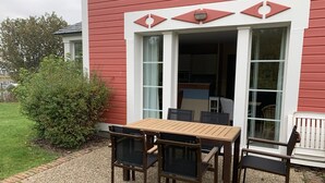 A red building with a wooden table and chairs outside. - Charming 3-bedroom house in Belle Dune (Fort-Mahon-Plage)