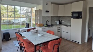 A modern kitchen with white cabinets, a marble countertop, and a large window overlooking a garden. - Charming 3-bedroom house in Belle Dune (Fort-Mahon-Plage)