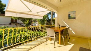 Un espacio al aire libre cubierto con una mesa, sillas y una barandilla amarilla, con vistas a zonas verdes.