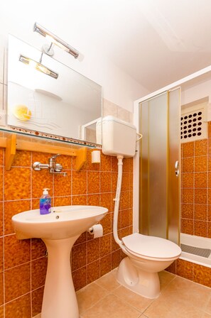 Et badeværelse med et konsolbordvask, toilet og brusekabine.