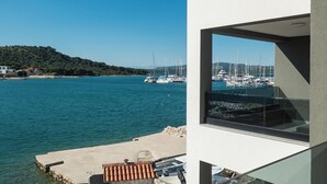 Un edificio moderno con un gran ventanal que da a un puerto deportivo con barcos.