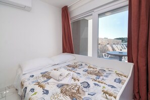 Ein Schlafzimmer mit Bett, Fenster und Ausblick nach draußen.