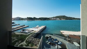 Vista de un puerto deportivo con barcos amarrados, un cielo azul despejado y un paisaje montañoso al fondo.