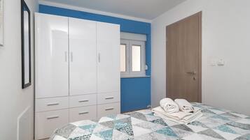 A bedroom with a bed, a wardrobe, a window, and a door.