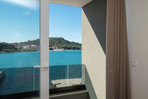 A balcony with a clear view of a body of water and a distant hill. - Apartments Villa Summertime (Tisno)