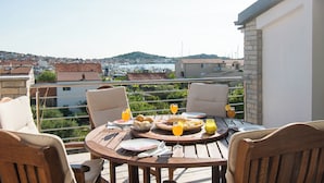 A terrace with a table set for breakfast, overlooking a marina and a town. - Apartment Villa Zlatna (Tisno)