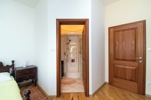 A bedroom with a wooden bed, a nightstand, a small rug, and a wooden door. - Apartment Villa Zlatna (Tisno)