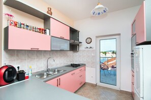 Une cuisine moderne avec des meubles roses, une cuisinière à gaz et un évier.