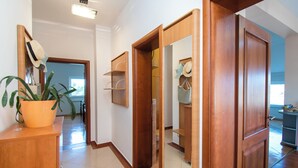A hallway with a wooden door, a potted plant, and a mirror with hats hanging. - Apartment Villa Zlatna (Tisno)