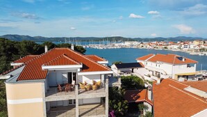 A coastal residential area with terracotta-tiled roofs, a marina, and a mountainous backdrop. - Apartment Villa Zlatna (Tisno)