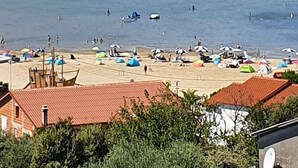 A coastal beach with rocky cliffs, clear blue water, and beach umbrellas. - Apartments Marin (Lopar)