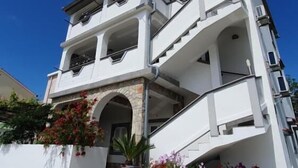 A multi-story building with balconies, a satellite dish, and flower planters. - Apartments Marin (Lopar)