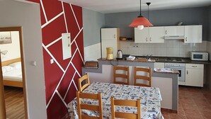 A compact kitchen with white cabinets, a red pendant light, and a tiled floor. - Apartments Marin (Lopar)