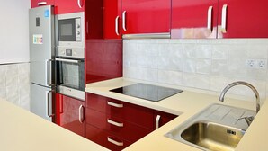 Una cocina moderna con armarios rojos, electrodomésticos de acero inoxidable y un lavamanos.