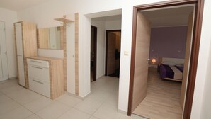A modern bedroom with a wooden dresser, a mirror, and a bed with a purple bedspread. - Villa Mirka (Barban)