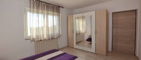 A bedroom with a bed, a wardrobe, a mirror, and a door.