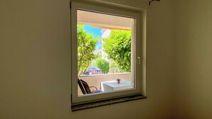 A window with a view of a balcony, a table, and a chair. - Apartment Brdar (Crikvenica)