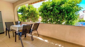 Ein Balkon mit Tisch, Stühlen, einer Topfpflanze und Blick auf ein Gebäude.