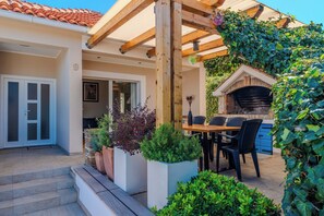 A covered patio area with a wooden pergola, outdoor seating, and a brick oven. - Apartment Iva (Zadar)
