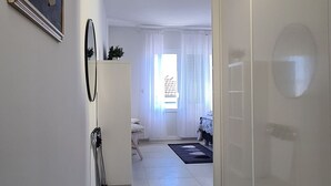 A hallway with a sliding door, a framed picture on the wall, and a view into a room with a bed and curtains. - Apartments Pleasures (Jelsa)